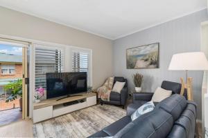 a living room with a couch and a flat screen tv at Coledale Beach Escape - Modern Comfort by the Sea in Coledale
