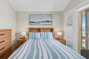 a bedroom with a bed with blue and white stripes at Coledale Beach Escape - Modern Comfort by the Sea in Coledale