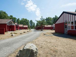 a dirt road next to a red building with a rock at Holiday home with waterpark access in Væggerløse in Marielyst