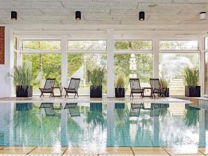 a pool with chairs in a room with windows at 6 person holiday home in Gilleleje in Gilleleje +25 photos