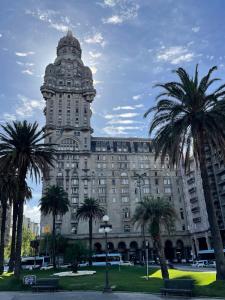un grand bâtiment avec des palmiers devant dans l'établissement Excepcional apartamento en Palacio Salvo, à Montevideo