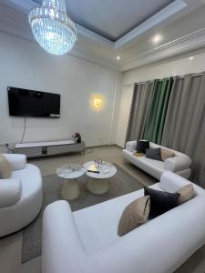 a living room with white furniture and a flat screen tv at Appartement au centre-ville in Brazzaville +3 photos