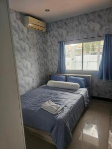 een slaapkamer met een bed met blauwe lakens en een raam bij Barn sabai pool villa in Ban Wang Phong