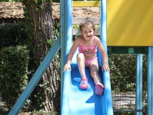 a little girl sitting on a slide on a playground at Mobil-home 2 chambres avec terrasse - API-1-52-456 in La Mothe-Achard