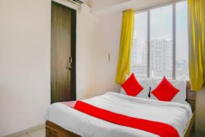 浦那Collection O Baner Hillview Pune Formerly Siri Lodge的一间卧室，有一张带红色枕头的床和一扇窗户 更多23张照片