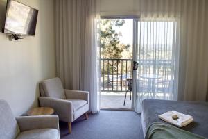 Habitación de hotel con cama, silla y balcón. en BATHURST GOLDFIELDS MOTEL at 428 CONROD STRAIGHT MOUNT PANORAMA, en Bathurst