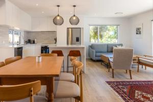 a kitchen and living room with a table and chairs at Bay Haven - Walk to Palm Beach in Waiheke Island