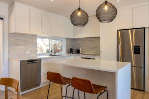 a kitchen with white cabinets and a large island with chairs at Bay Haven - Walk to Palm Beach in Waiheke Island +18 photos