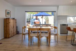 ein Esszimmer mit einem Tisch, Stühlen und einem blauen Sonnenschirm in der Unterkunft Bay Haven - Walk to Palm Beach in Waiheke Island + 18 Fotos