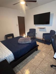 a bedroom with a bed and two chairs and a flat screen tv at Habitación Roble, cómoda y espaciosa in Saltillo