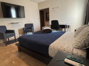 a bedroom with a bed with chairs and a tv at Habitación Roble, cómoda y espaciosa in Saltillo