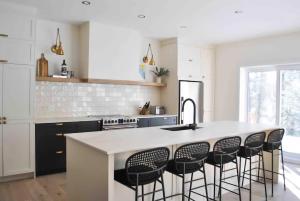 プティット・リヴィエール・サン・フランソワにあるChalet La Rocheuse et SPAの白い大きな島(黒い椅子付)のあるキッチン