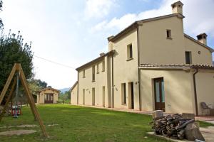 un gran edificio blanco con un patio con parque infantil en Locanda Montelippo, en Colbordolo