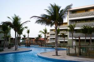 a swimming pool with palm trees in front of a building at Oásis Vistamar in Luis Correia