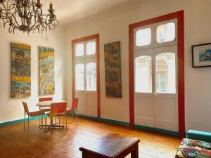 a living room with a table and chairs and windows at La Mancha Art Hostel in Valparaíso +2 photos