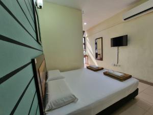 Un dormitorio con una cama blanca y un televisor. en BCIC Lodge, en Kuantan