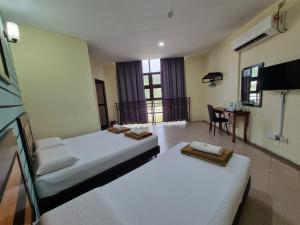 Un dormitorio con dos camas y una mesa con una silla. en BCIC Lodge, en Kuantan