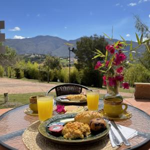 ein Tisch mit Tellern voller Essen und Gläsern mit Orangensaft in der Unterkunft Hacienda Cascanueces in Villa de Leyva