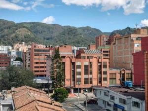 a city with buildings and mountains in the background at Luxury Triplex Penthouse with Balcony and Stunning Mountain Views in Bogotá