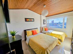 a bedroom with two beds and a window at Luxury Triplex Penthouse with Balcony and Stunning Mountain Views in Bogotá