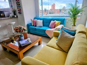 a living room with a blue couch and a coffee table at Luxury Triplex Penthouse with Balcony and Stunning Mountain Views in Bogotá