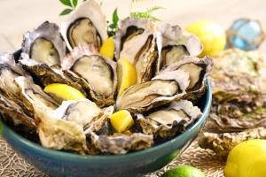 a bowl of oysters and lemons on a table at KAMENOI HOTEL Kujukuri in Asahi