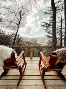 two rocking chairs on a wooden deck with mountains in the background at Stunning Pet-Friendly Treehouse for Relaxing Glamping Retreats in North Carolina in Retreat +94 photos