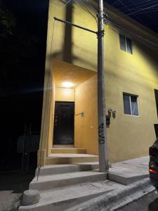 um edifício amarelo com uma porta preta e escadas em The CaSa em Saltillo