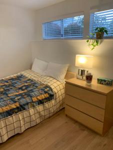 Un dormitorio con una cama y una mesita de noche con una lámpara. en Tempe, en North Vancouver