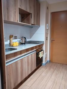 a kitchen with wooden cabinets and a wooden floor at Departamento para Dos in Temuco
