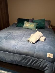 a bed with two pillows and two towels on it at Departamento para Dos in Temuco