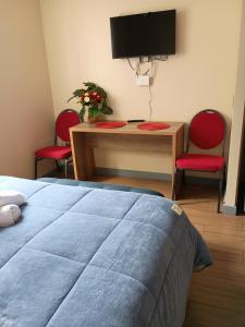 a bedroom with a bed and a table with two red chairs at Departamento para Dos in Temuco