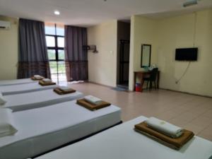 Habitación de hotel con 4 camas y TV en BCIC Lodge, en Kuantan