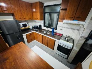 Elle comprend une petite cuisine avec des placards en bois et un réfrigérateur noir. dans l'établissement Amplio Departamento, à Cañada de Gómez