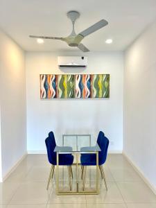 a dining room with a glass table and blue chairs at D Pristine 4 bedroom apartment 2025 opposite legoland and medini in Iskandar Puteri