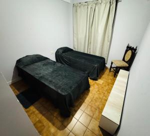 un salon avec deux lits et une chaise dans l'établissement Amplio Departamento, à Cañada de Gómez