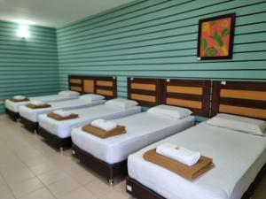 una habitación con cuatro camas alineadas contra una pared en BCIC Lodge, en Kuantan