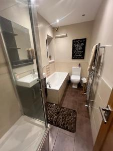 a bathroom with a tub and a sink and a toilet at Modern Flat with Wembley Stadium View in London