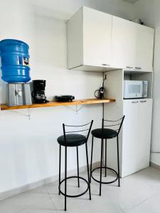 a kitchen with two chairs and a counter with a microwave at Quero mais arraial suites in Arraial do Cabo +32 photos