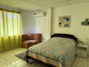a bedroom with a bed and a chair at Los mangos Posadamanabita in Portoviejo +21 photos