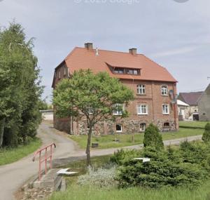 a large brick house with a tree in front of it at Apartament Relaks i Aktywny Wypoczynek 