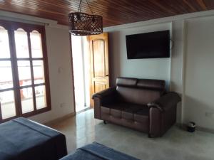 a living room with a leather couch and a television at CIELITO LINDO in Santa Rosa de Cabal
