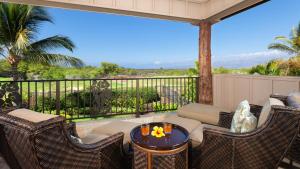 Un patio con una mesa y sillas en un balcón. en LOTUS PAD Vibrant KaMilo 4BR Home with Heated Pool and Spa, en Waikoloa