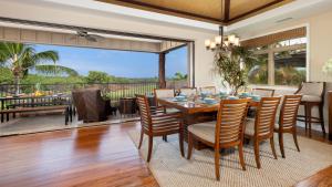 Un comedor con mesa y sillas y una gran ventana. en LOTUS PAD Vibrant KaMilo 4BR Home with Heated Pool and Spa, en Waikoloa