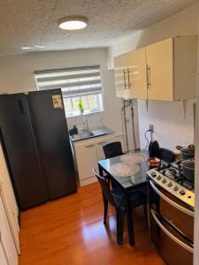 蓬塔阿雷纳斯Casa Patagonica的厨房配有桌子和黑冰箱。