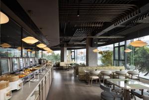 a restaurant with tables and chairs and windows at YOUNG Hotel Guilin -Mixc Mall in Guilin