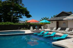 a swimming pool with lounge chairs and umbrellas at SUNSET VILLA Spacious Mauna Lani 3BR Home With Private Beach Club in Waikoloa