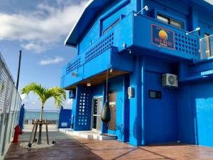 a blue building next to the beach with a palm tree at SEA BASE Onna in Onna