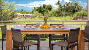 a wooden table with chairs and fruit on a patio at SEA TO SKY Stunning 3BR Villages Home With Three Master Suites in Waikoloa