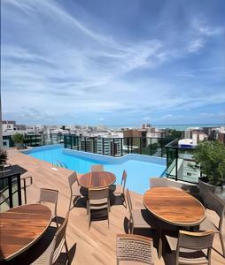 a patio with tables and chairs and a pool at Apt sensacional Liv Residence pertinho da praia ! in Maceió